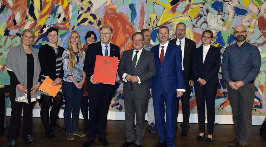 WHKT-Präsident Hans Hund (vorne l.) und WHKT-Hauptgeschäftsführer Reiner Nolten (vorne r.) überreichen Ministerpräsident Armin Laschet (vorne m.) das »Goldene Landesbuch von NRW«.