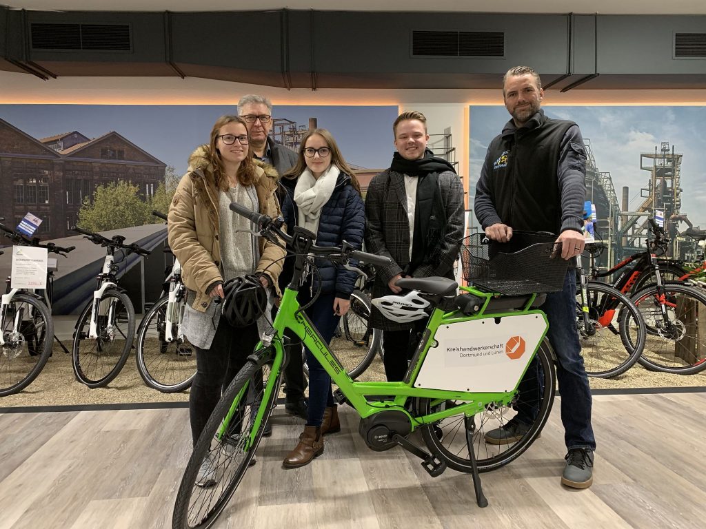 Die Auszubildenden Judith Oertel, Valentina Čalic und Melvin Kilian (v. l.) durften das E-Bike schon beim Kauf testen. Klaus Gerhardy vom Radhaus Gerhardy (r.) übergab das neue Rad an Geschäftsführer Volker Walters (2. v. l.). (Foto: Kreishandwerkerschaft Dortmund und Lünen)