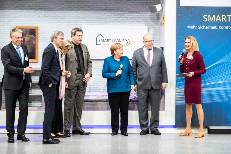 Vor dem E-Haus des ZVEH (v. l. n. r.): Hans-Georg Krabbe (ABB AG), Achim Berg (Bitkom), Anja Karliczek (Bundesministerin für Bildung und Forschung), Markus Söder (Bayerischer Ministerpräsident), Bundeskanzlerin Dr. Angela Merkel, Bundeswirtschaftsminister Peter Altmaier und Ingeborg Esser (GdW) Bild: Wirtschaftsinitiative Smart Living / Lena Siebrasse