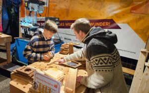 Impressionen aus der Mitmachwerkstatt: Vom Bohren der Löcher für den Kerzenhalter bis zur Arbeit mit dem Schleifklotz – das Hantieren mit Holz machte sowohl den kleinen als auch großen Besucherinnen und Besuchern viel Spaß. Foto: Tischler NRW